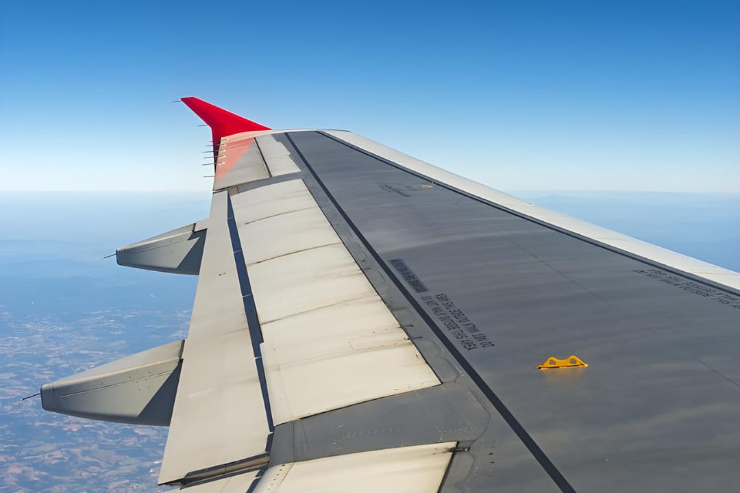 بال هواپیما (Airplane Wing) در میان آسمان آبی و ابرها