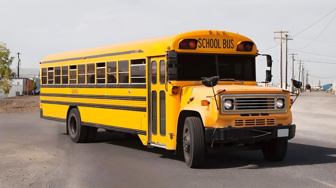 اتوبوس زرد مدرسه (School Bus) کلاسیک در یک جاده آسفالت