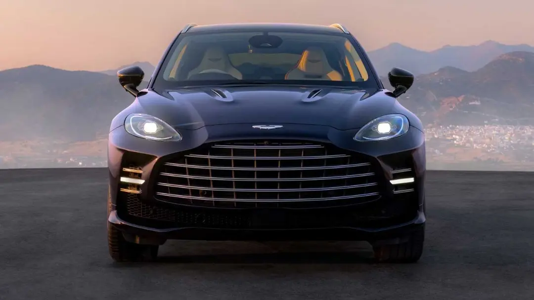 خودرو آستون‌مارتین (Aston Martin) DBX GT با چراغ‌های روشن در مقابل کوه‌ها