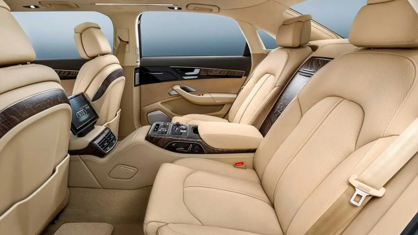کابین عقب خودروی لوکس آئودی (Audi) با صندلی‌های چرمی کرم‌رنگ و تزئینات چوبی