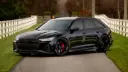 خودرو مشکی رنگ آئودی RS 6 آوانت (Audi RS 6 Avant) در جاده‌ای میان حصار سفید