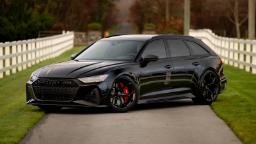خودرو مشکی رنگ آئودی RS 6 آوانت (Audi RS 6 Avant) در جاده‌ای میان حصار سفید