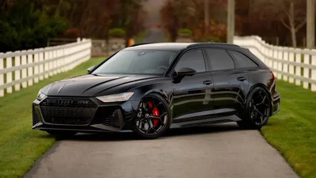 خودرو مشکی رنگ آئودی RS 6 آوانت (Audi RS 6 Avant) در جاده‌ای میان حصار سفید