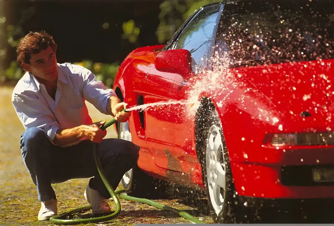 آیرتون سنا (Ayrton Senna) در حال شستن خودروی قرمز هوندا NSX با شلنگ آب