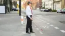 فرد نابینا (Blind person) با عصای سفید در حال عبور از پیاده‌رو