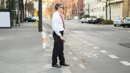 فرد نابینا (Blind person) با عصای سفید در حال عبور از پیاده‌رو