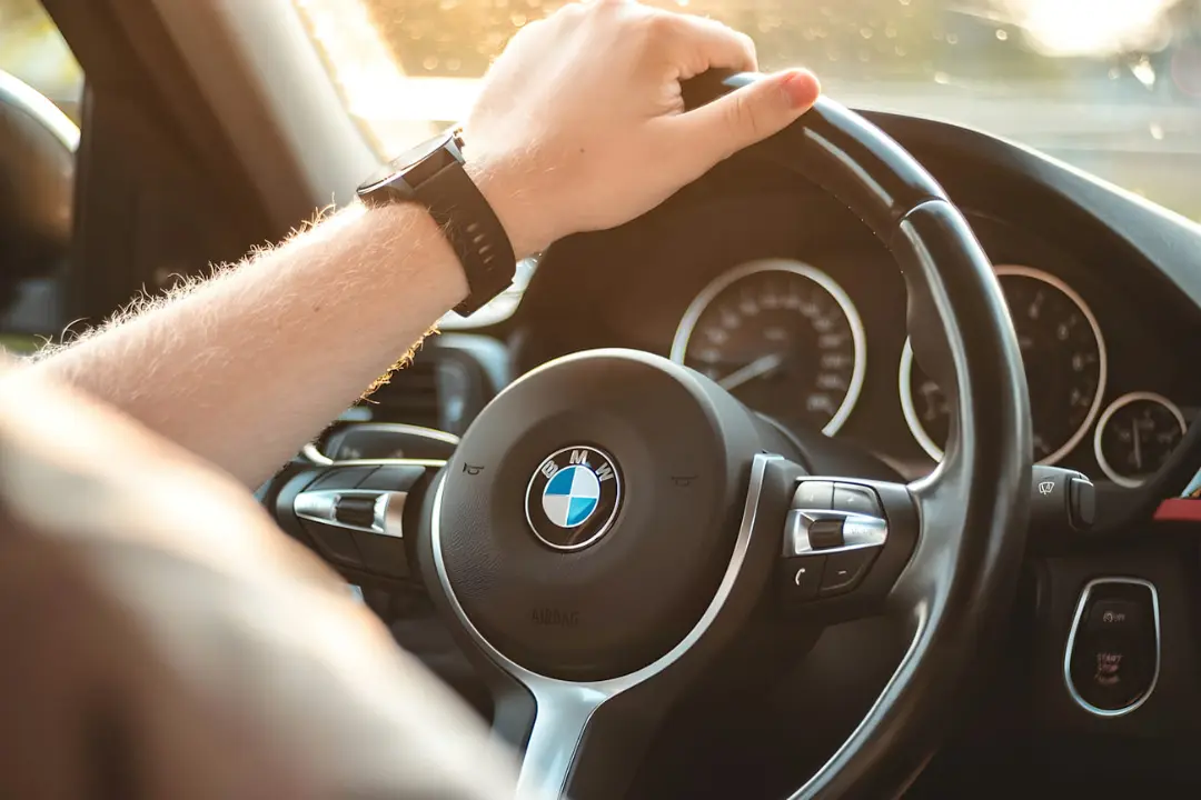 دست راننده روی فرمان خودرو بی‌ام دبلیو (BMW) در حال رانندگی