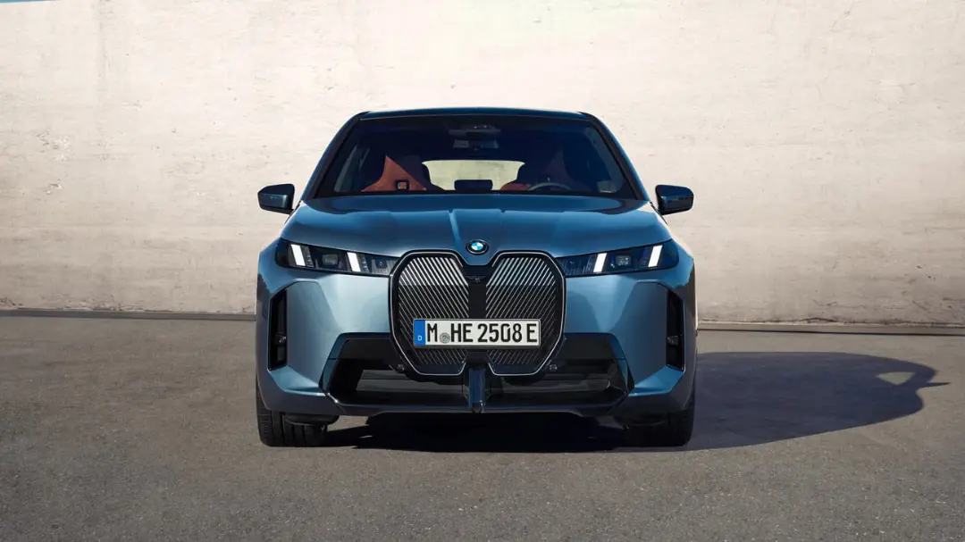 خودروی برقی بی‌ام‌و (BMW iX) با جلوپنجره بزرگ و چراغ‌های LED در مقابل دیوار
