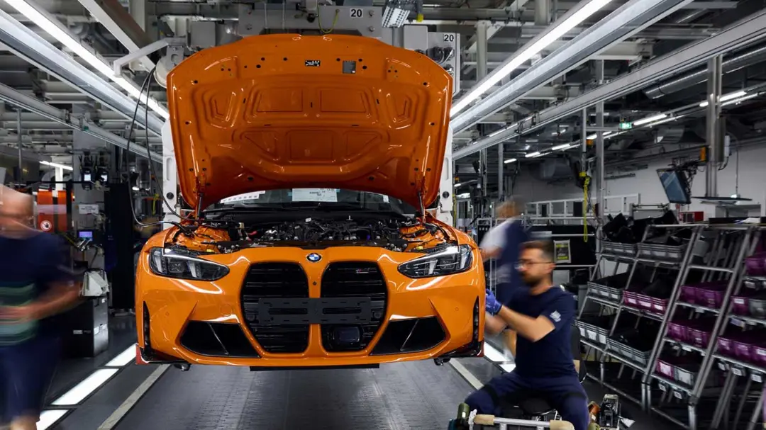 خودروی نارنجی رنگ بی‌ام‌و (BMW M) با کاپوت باز در خط تولید