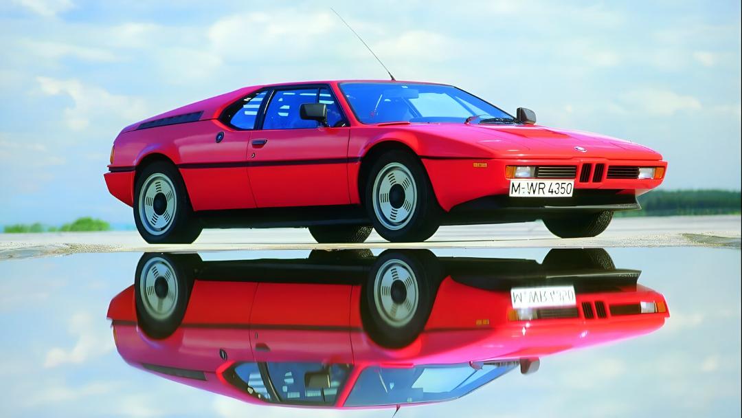خودرو قرمز رنگ بی‌ام‌و ام یک (BMW M1) روی سطح بازتابنده