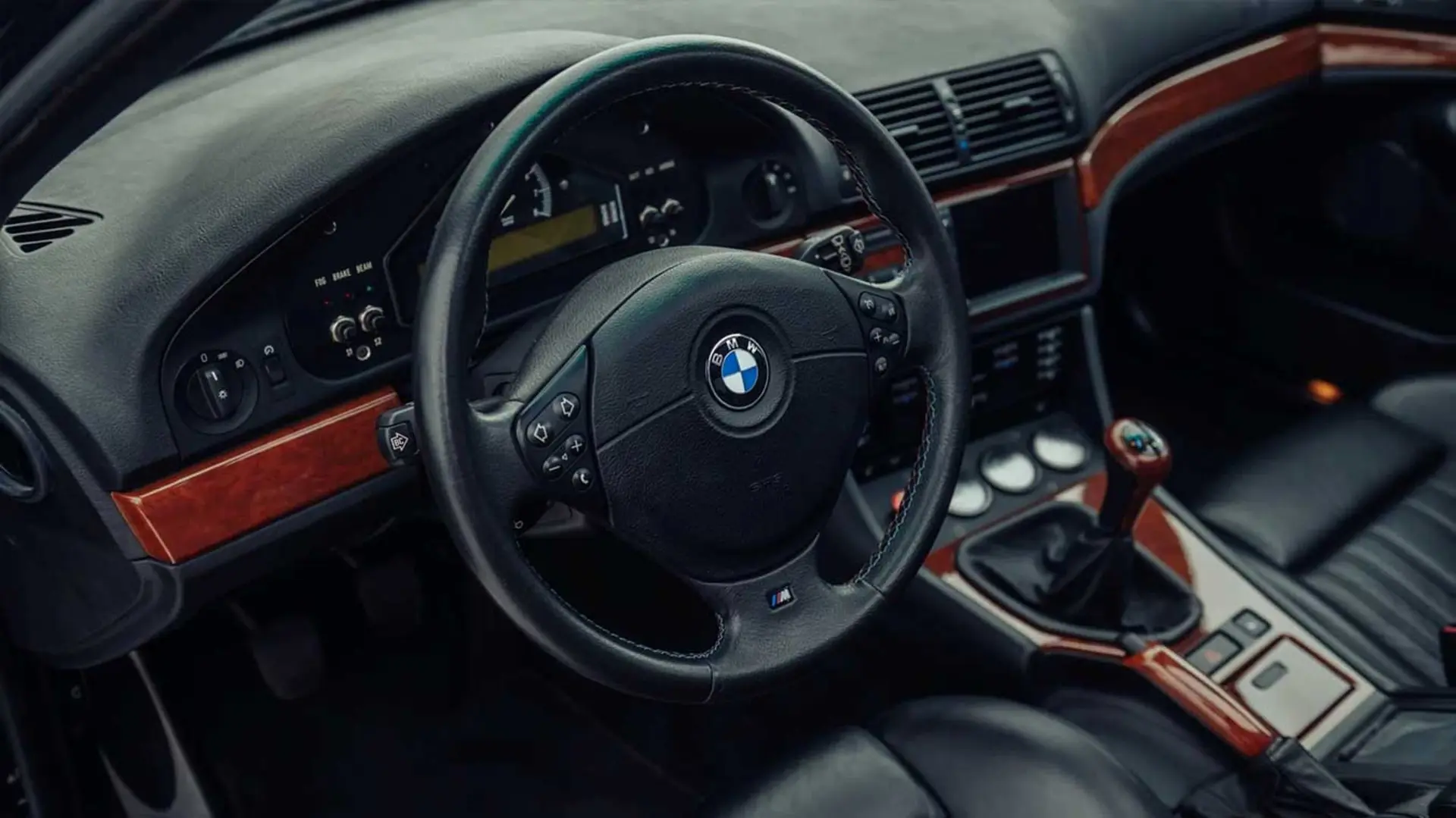 نمای داشبورد و فرمان خودروی بی‌ام‌و (BMW) M5 با تریم چوبی