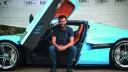 خودروی بوگاتی (Bugatti) آبی‌رنگ با درهای بال پروانه‌ای و مردی نشسته در کنار آن