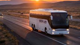 اتوبوس مسافربری سفید برند Horizon Lines در حال حرکت در جاده کوهستانی هنگام غروب