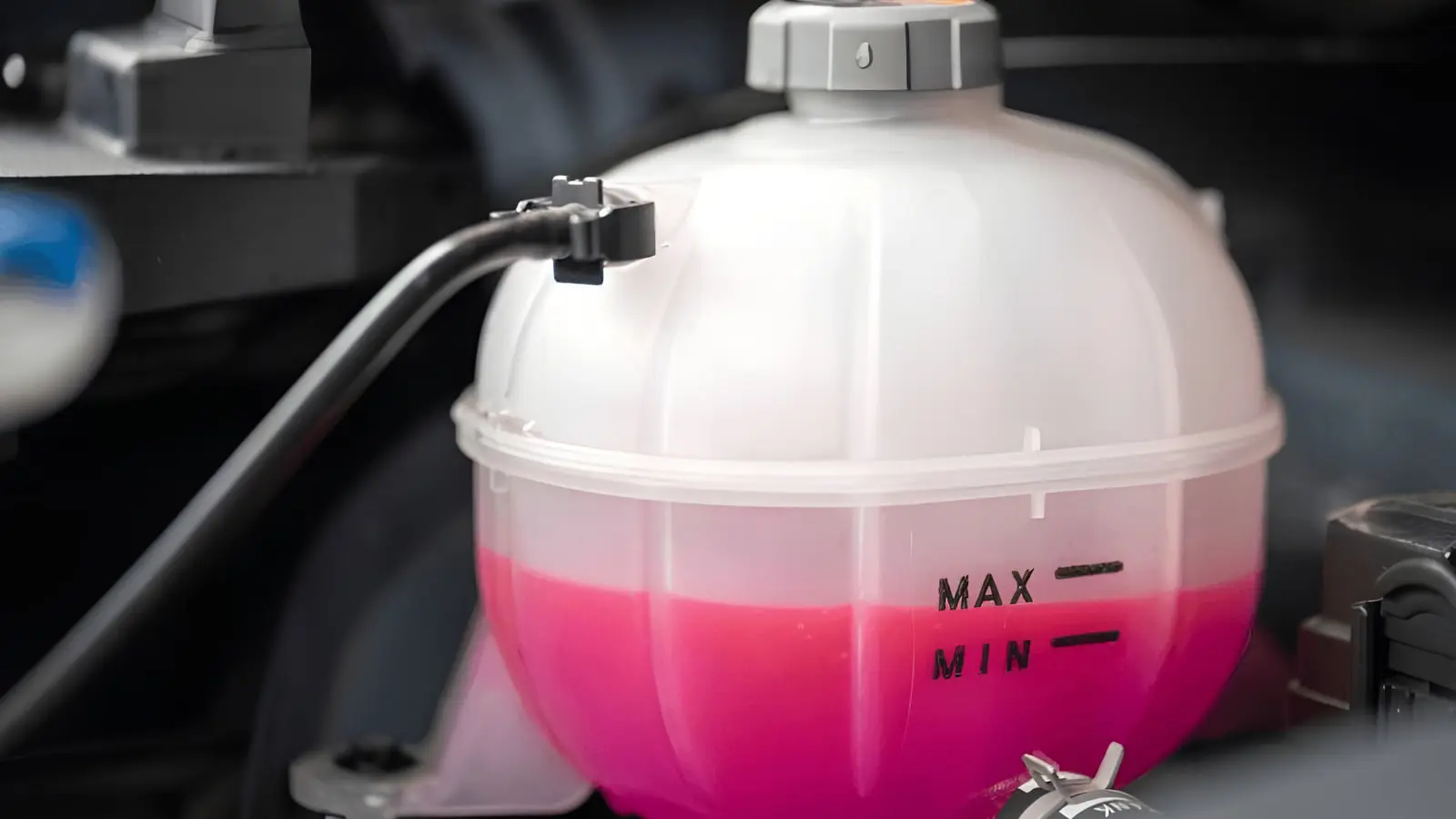 مخزن پلاستیکی ضدیخ (Antifreeze) با مایع صورتی رنگ در موتور خودرو