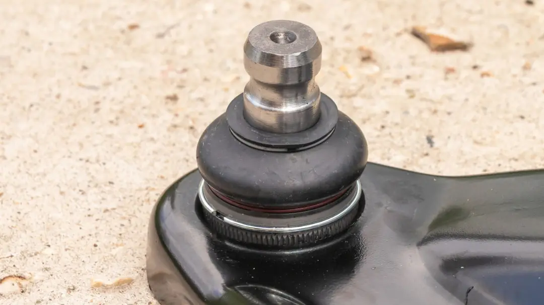 سیبک خودرو (Ball Joint) متصل به قطعه سیاه رنگ روی زمین