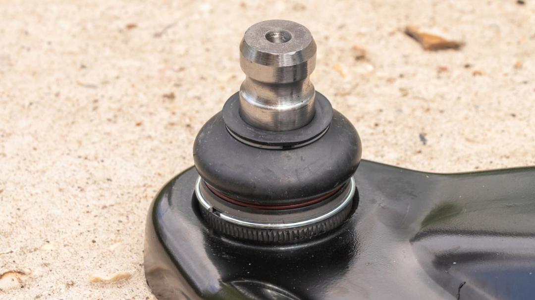 سیبک خودرو (Ball Joint) متصل به قطعه سیاه رنگ روی زمین