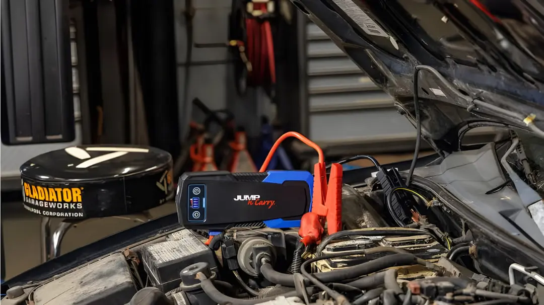 استارت کمکی (Jump Starter) متصل به ترمینال‌های باتری خودرو برای روشن کردن موتور