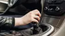 دست راننده روی دسته دنده خودرو برای تعویض دنده