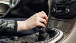 دست راننده روی دسته دنده خودرو برای تعویض دنده