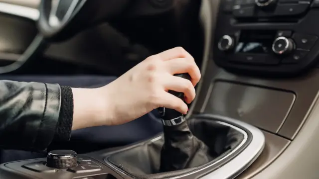 دست راننده روی دسته دنده خودرو برای تعویض دنده