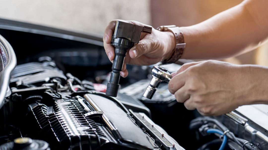 کوئل (Ignition Coil) در حال نصب روی موتور خودرو توسط تعمیرکار