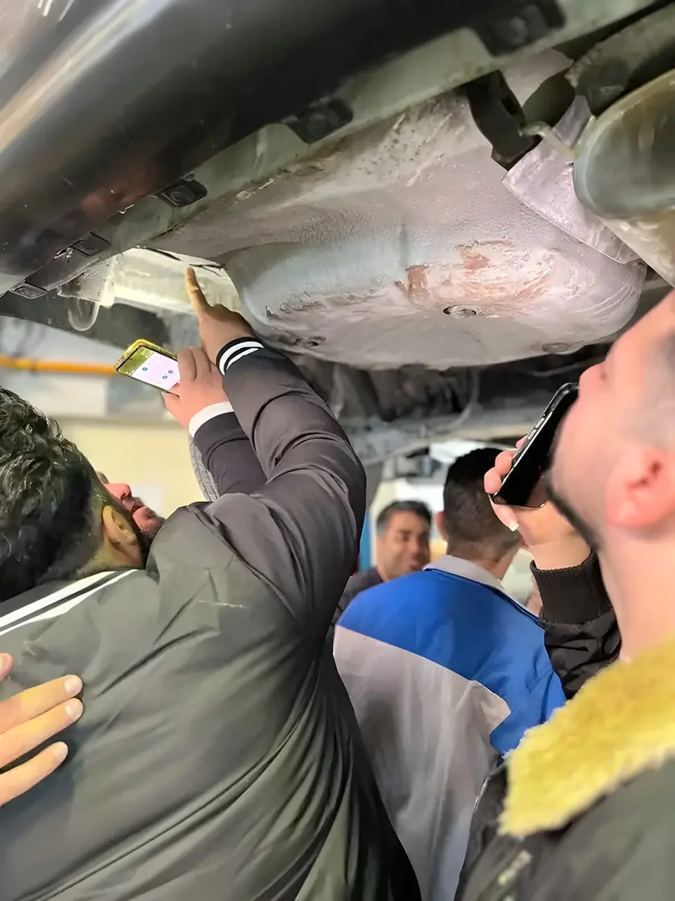 دست کارشناس خودرو در حال استفاده از دستگاه ضخامت‌سنج برای بررسی بدنه
