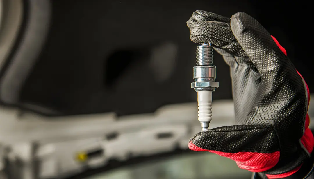 شمع موتور (Spark Plug) در دست تعمیرکار با دستکش محافظ