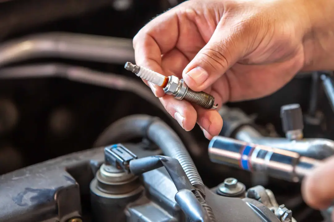 شمع خودرو (Spark Plug) در دست تعمیرکار برای بررسی سلامت