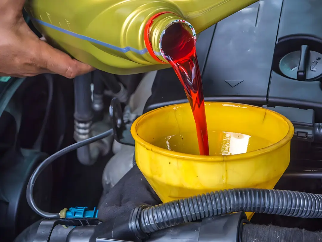 روغن قرمز رنگ گیربکس در حال ریخته شدن در ظرف زرد رنگ
