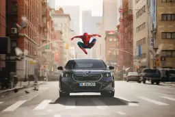 مرد عنکبوتی (Spider-Man) در حال پریدن بالای یک خودروی BMW سیاه در خیابان