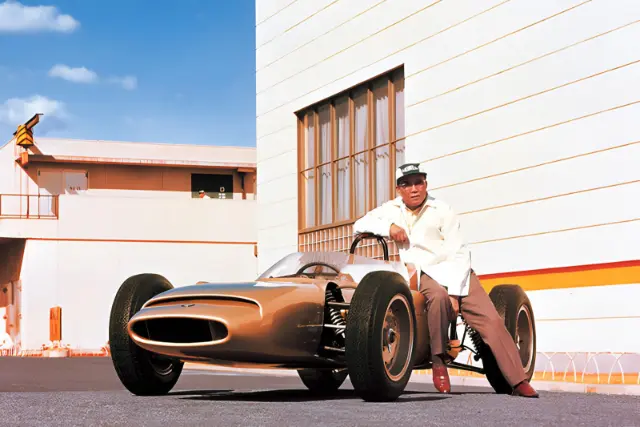 ماشین مسابقه‌ای کلاسیک (Classic Racing Car) در کنار مهندسی که در کنار آن ایستاده است