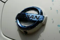 لوگوی نیسان (Nissan) روی بدنه سفید خودرو با قطرات آب