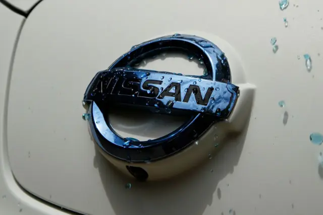 لوگوی نیسان (Nissan) روی بدنه سفید خودرو با قطرات آب