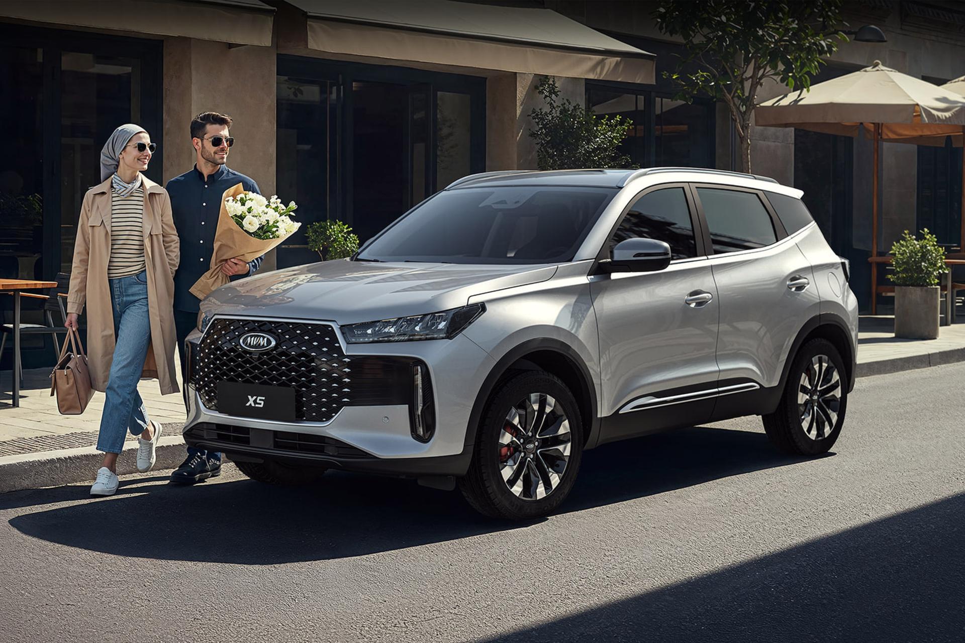 خودرو ام‌وی‌ام ایکس‌۵ (MG X5) نقره‌ای در کنار یک زوج در خیابان