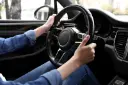 دست‌های یک راننده روی فرمان خودرو در حین حرکت