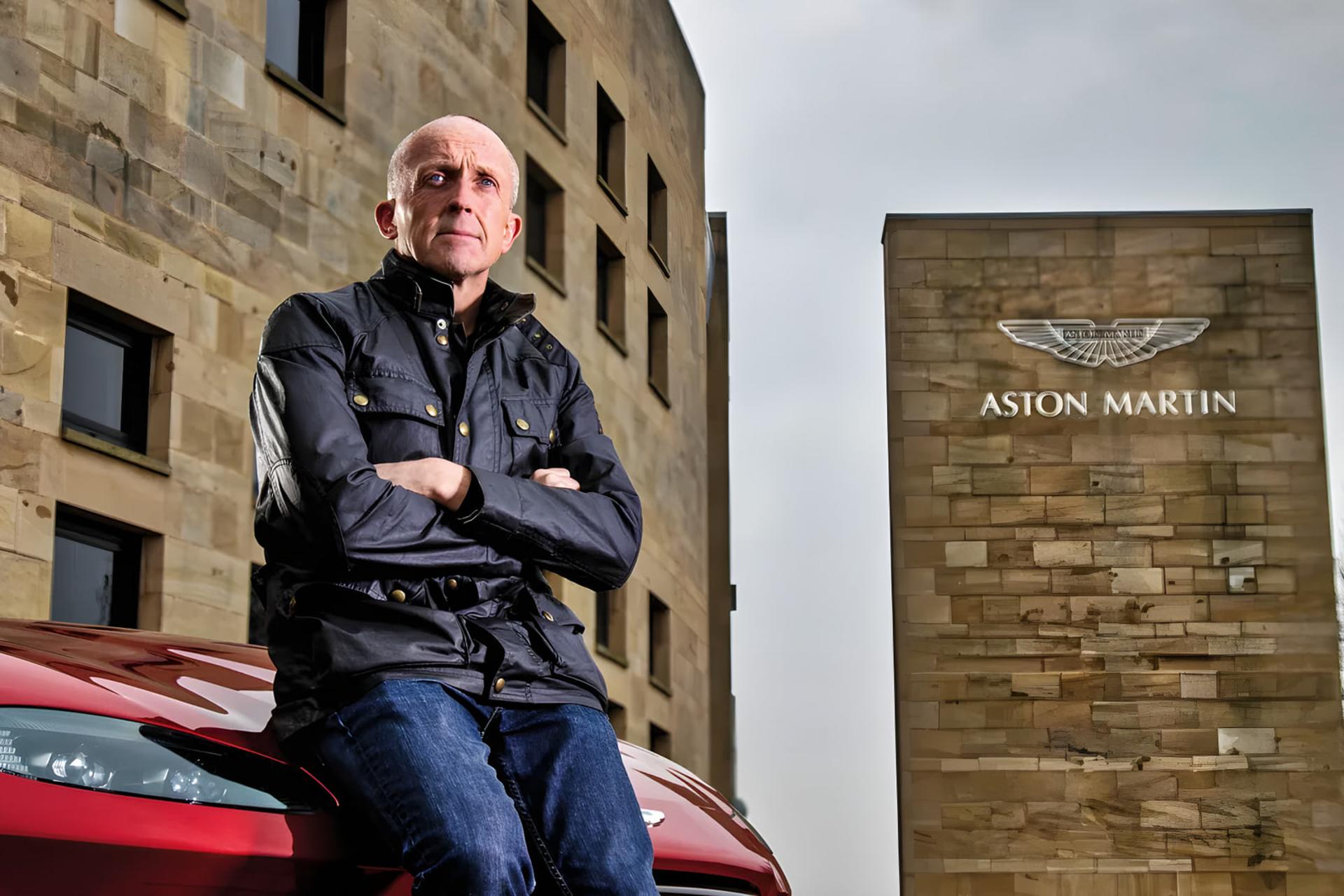 کریس گودوین (Chris Goodwin) با دست‌های گره‌خورده در مقابل ساختمان استون مارتین (Aston Martin)