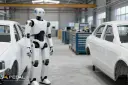 ربات انسان‌نما (Humanoid Robot) در میان خودروهای سفید در کارخانه خودروسازی