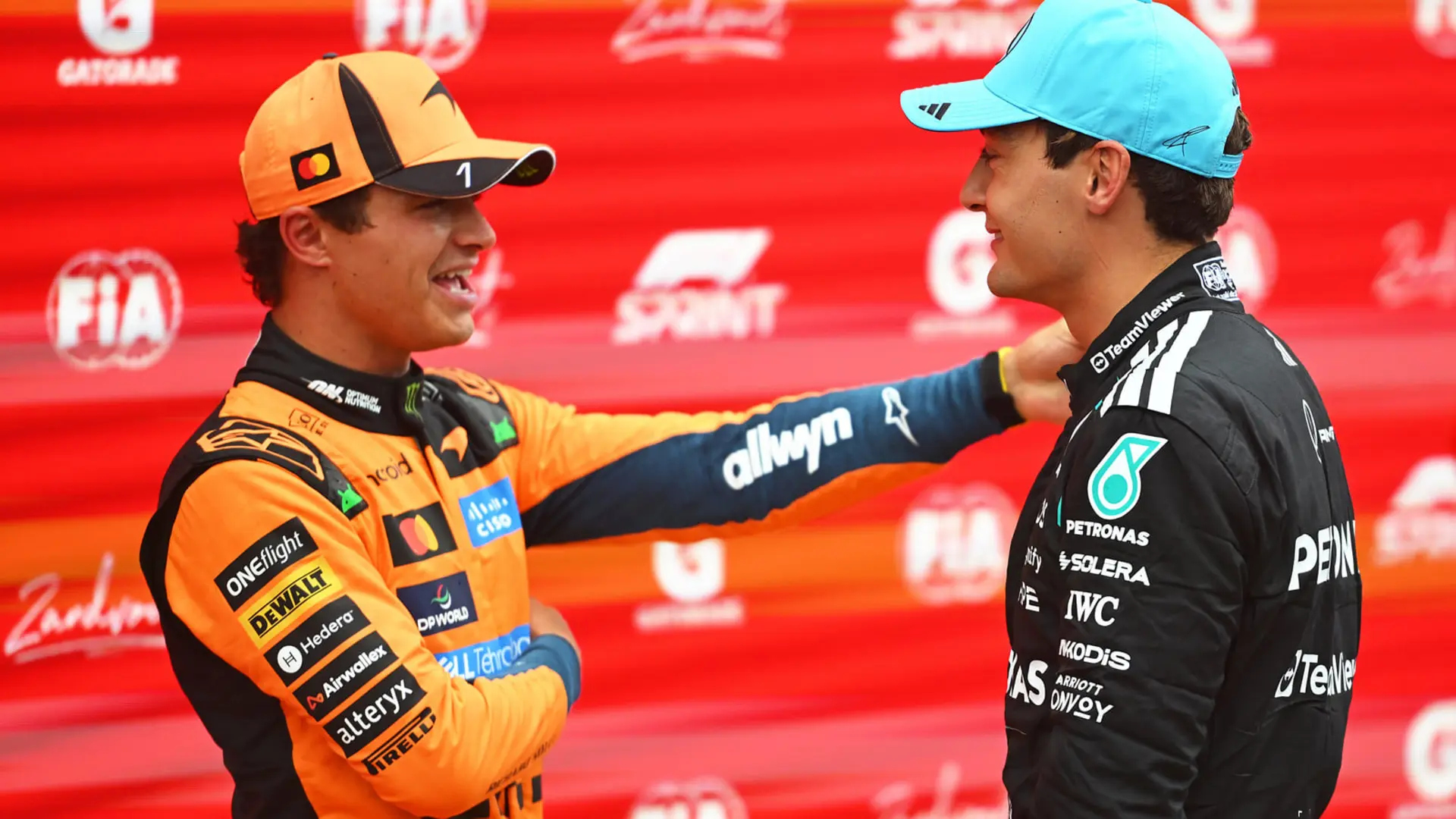 لاندو نوریس (Lando Norris) با لباس نارنجی مک‌لارن در حال گفت‌و‌گو با جورج راسل تیم مرسدس