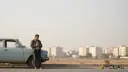 مردی در کنار خودروی قدیمی در حال استفاده از گوشی هوشمند
