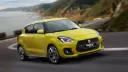 خودروی کامپکت سوزوکی سوئیفت (Suzuki Swift) زرد رنگ در حال حرکت در جاده ساحلی