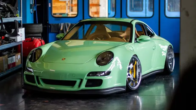 خودروی پورشه ۹۱۱ (Porsche 911) با رنگ سبز روشن و بدنه اصلاح‌شده در گاراژ