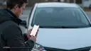 مردی در حال بررسی صورت‌حساب شارژ خودروی برقی با گوشی هوشمند
