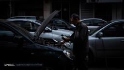مردی در حال بررسی موتور خودروی شخصی با کاپوت باز
