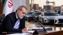 مردی در حال نوشتن اسناد در کنار خودروهای وارداتی در گمرک