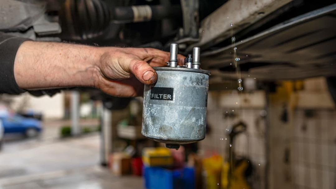 فیلتر بنزین (Fuel Filter) کثیف و آسیب‌دیده در دست تعمیرکار خودرو