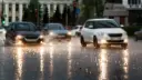 خودروهای در حال حرکت در جاده‌ای خیس و بارانی با نور چراغ‌ها