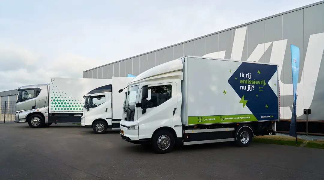 کامیون‌های سنگین برقی (Electric Trucks) سفید و سبز در مقابل یک انبار بزرگ