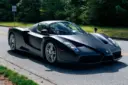 فراری انزو (Ferrari Enzo) با رنگ مشکی مات در جاده‌ای میان درختان