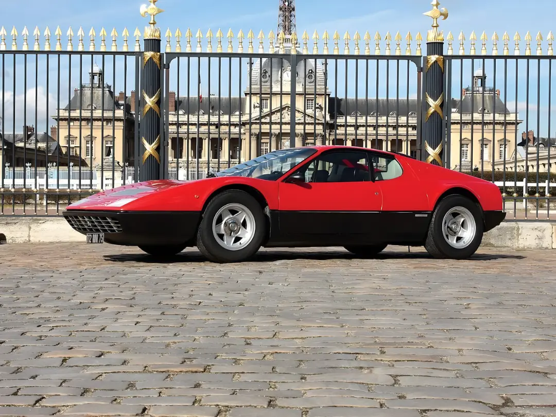 خودرو قرمز فراری (Ferrari) مدل F102 با بدنه دو رنگ در مقابل یک عمارت تاریخی