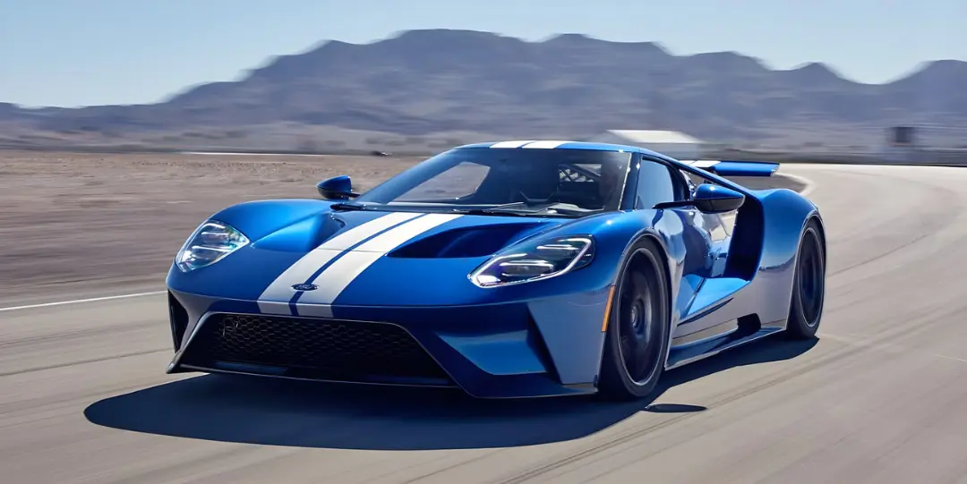 خودرو سوپراسپرت فورد GT (Ford GT) آبی با خطوط سفید در حال حرکت در پیست مسابقه
